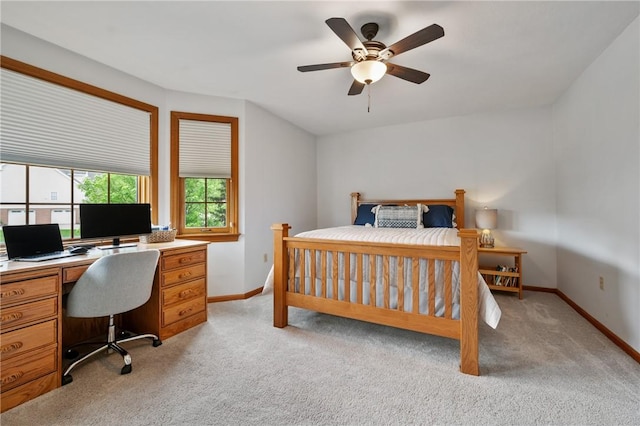 bedroom featuring light carpet, a desk, and baseboards