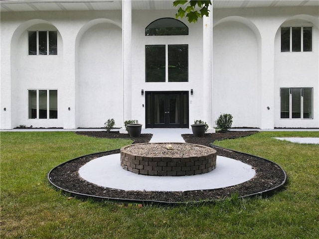 property entrance with french doors, stucco siding, and a yard