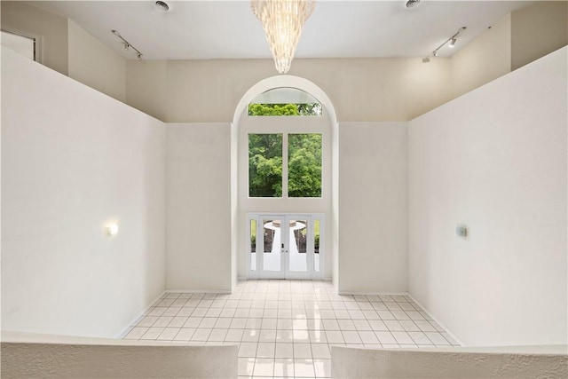 tiled spare room featuring rail lighting, french doors, and a high ceiling