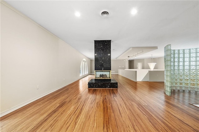 living area with wood finished floors, a multi sided fireplace, and baseboards
