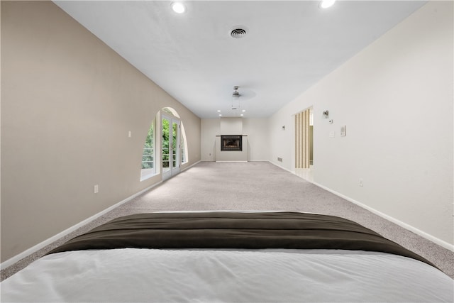 living room featuring carpet, a glass covered fireplace, baseboards, and recessed lighting