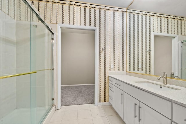 full bath with a stall shower, vanity, baseboards, tile patterned floors, and wallpapered walls
