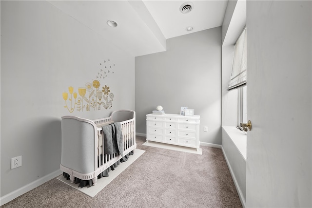 carpeted bedroom with a crib and baseboards