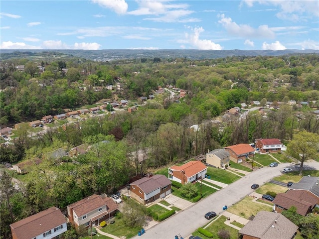 view of property location with nearby suburban area and a heavily wooded area