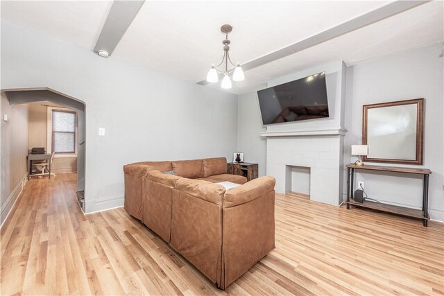 living area with light wood-style floors, arched walkways, baseboards, and a fireplace