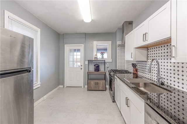 kitchen with appliances with stainless steel finishes, a sink, decorative backsplash, white cabinetry, and baseboards