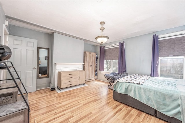bedroom with light wood-style floors, a baseboard heating unit, and baseboards
