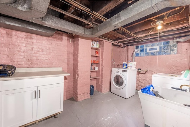 washroom with washing machine and dryer, cabinet space, and brick wall