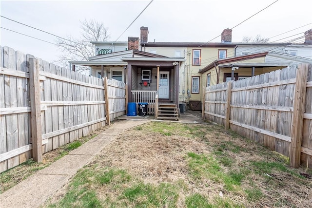 back of property featuring a fenced backyard and a porch