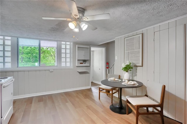 dining room featuring light wood finished floors, a ceiling fan, a textured ceiling, and baseboards