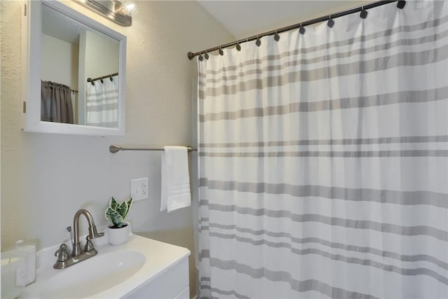 bathroom with vanity, curtained shower, and a textured wall