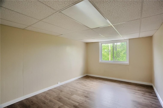 spare room featuring a paneled ceiling, wood finished floors, and baseboards