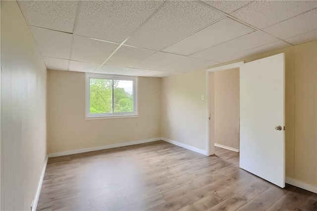 unfurnished room featuring a drop ceiling, wood finished floors, and baseboards