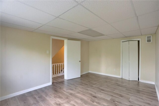 spare room featuring wood finished floors, a drop ceiling, and baseboards