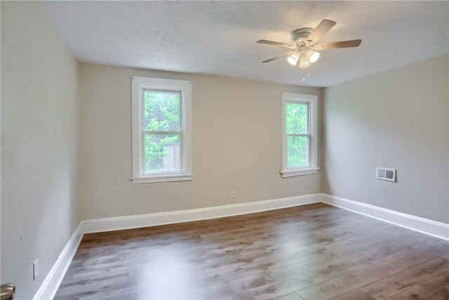 unfurnished room featuring healthy amount of natural light, wood finished floors, a ceiling fan, and baseboards