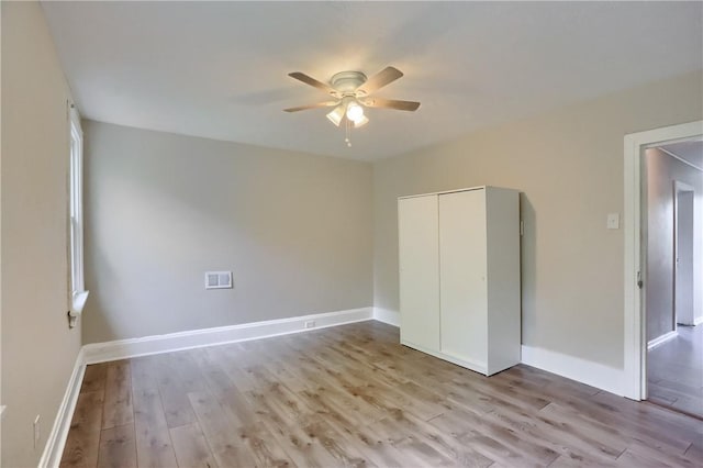 unfurnished bedroom with light wood-type flooring, a closet, ceiling fan, and baseboards
