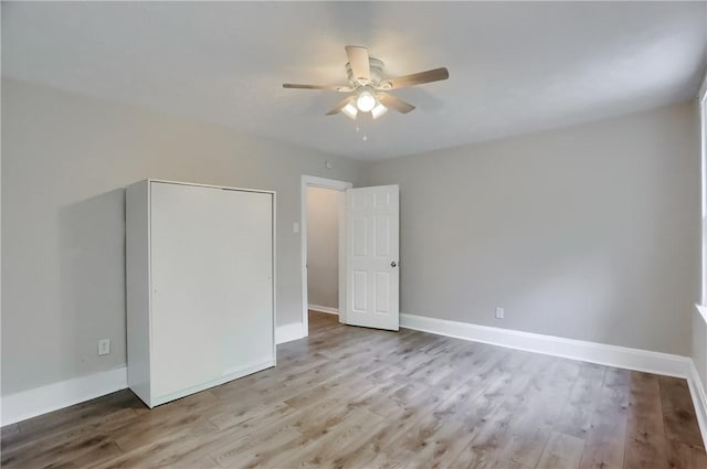 unfurnished bedroom with wood finished floors, baseboards, and a ceiling fan