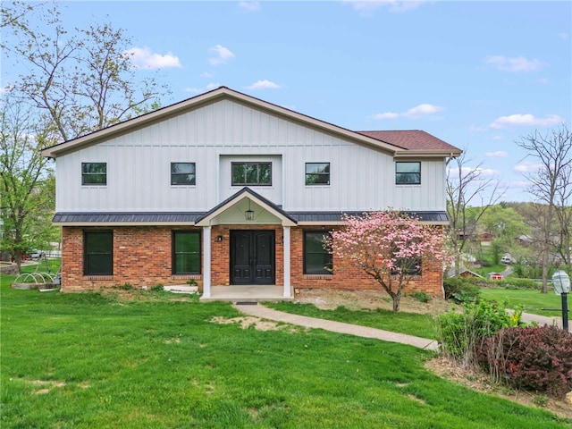 modern farmhouse style home featuring a front lawn, brick siding, and a standing seam roof