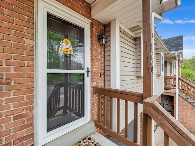 entrance to property with brick siding and a porch