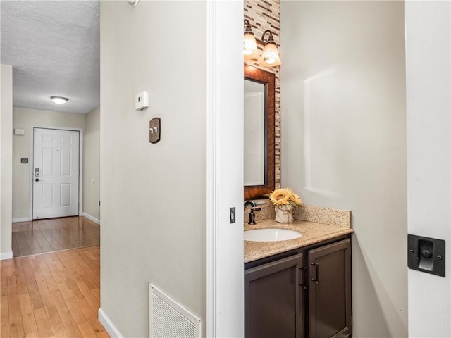 bathroom featuring baseboards, vanity, wood finished floors, and a textured ceiling