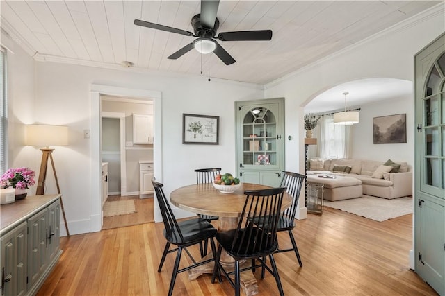 dining area featuring ceiling fan, light wood-style floors, arched walkways, ornamental molding, and wood ceiling