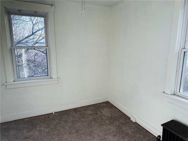 empty room featuring dark carpet, plenty of natural light, and baseboards
