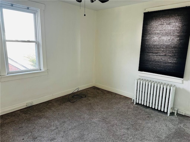 empty room with radiator heating unit, carpet flooring, ceiling fan, and baseboards