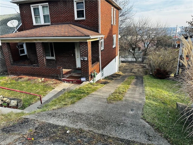 view of front of property with brick siding, covered porch, a shingled roof, and driveway