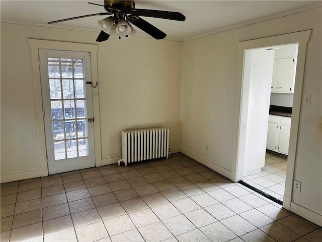 spare room with radiator, ornamental molding, light tile patterned floors, ceiling fan, and baseboards