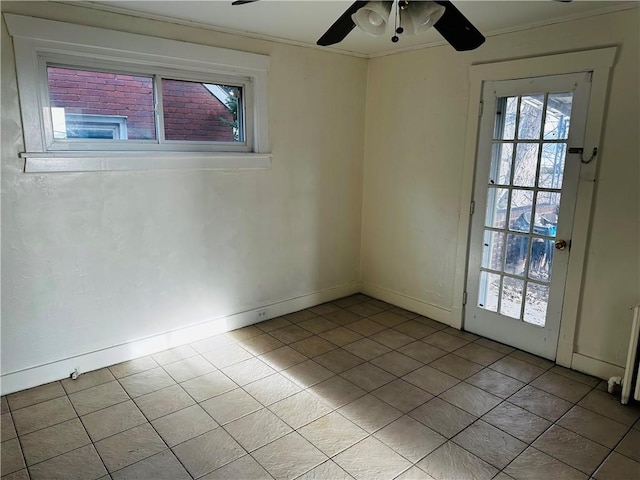 empty room with light tile patterned floors, a ceiling fan, plenty of natural light, baseboards, and ornamental molding