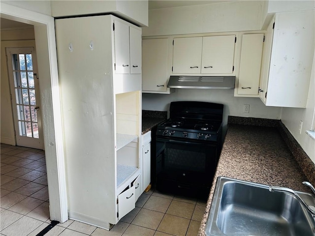 kitchen featuring black range with gas cooktop, under cabinet range hood, a sink, dark countertops, and light tile patterned flooring