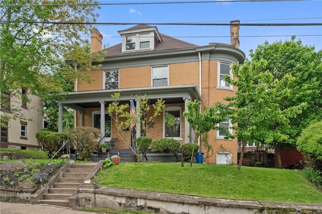 american foursquare style home featuring brick siding, a chimney, a porch, and stairway