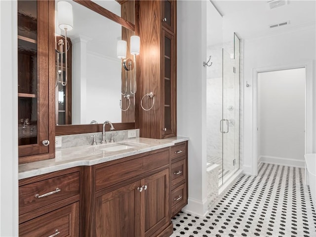 bathroom featuring a stall shower, baseboards, vanity, crown molding, and tile patterned flooring