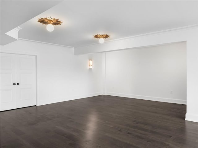 spare room with crown molding, dark wood-type flooring, and baseboards