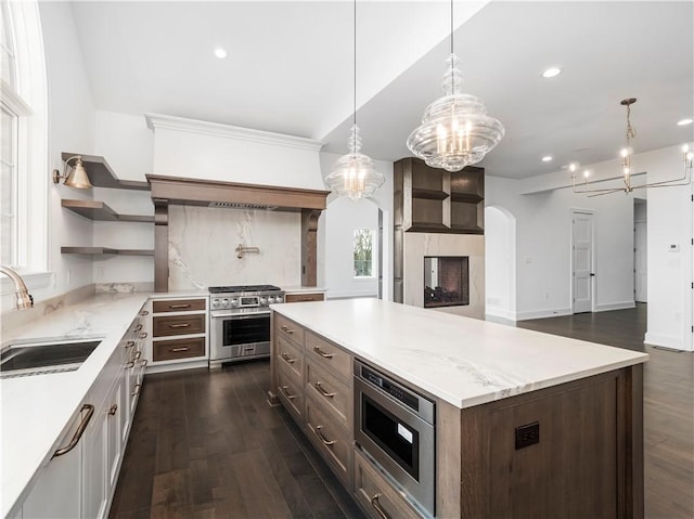 kitchen with a sink, appliances with stainless steel finishes, arched walkways, a chandelier, and recessed lighting