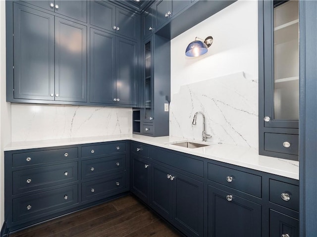 kitchen with a sink, dark wood-style floors, tasteful backsplash, and glass insert cabinets