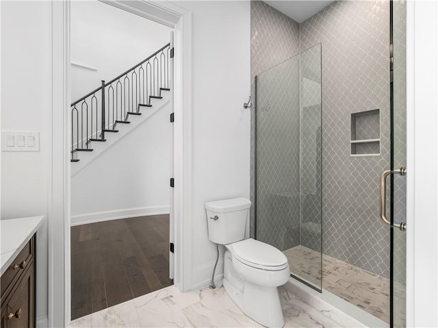 full bath with a shower stall, marble look tile flooring, baseboards, toilet, and vanity
