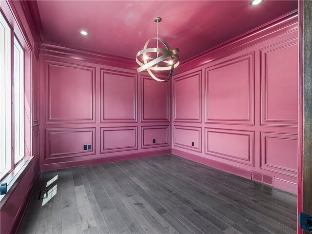 empty room with a decorative wall, a chandelier, ornamental molding, recessed lighting, and dark wood finished floors