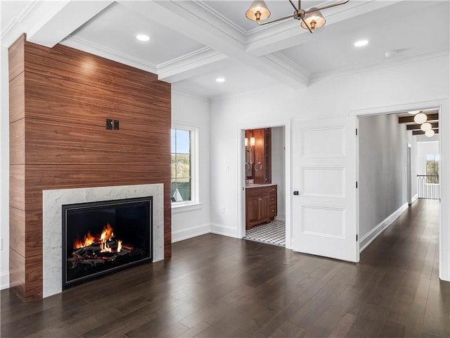 unfurnished living room featuring beamed ceiling, ornamental molding, wood finished floors, a high end fireplace, and baseboards