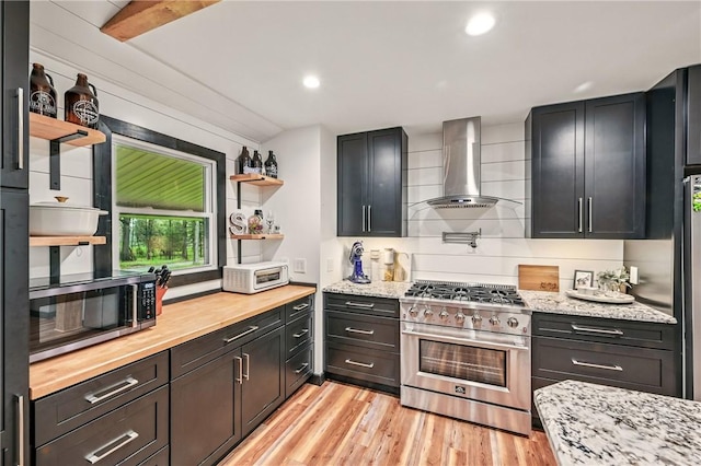 kitchen with appliances with stainless steel finishes, wall chimney range hood, open shelves, light wood-style floors, and recessed lighting