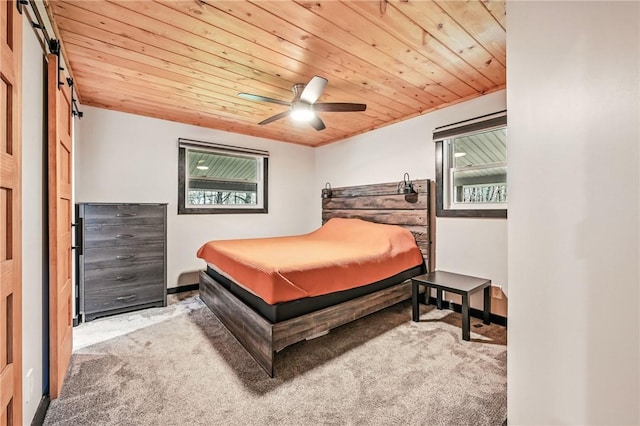 bedroom featuring carpet floors, wood ceiling, a barn door, ceiling fan, and baseboards