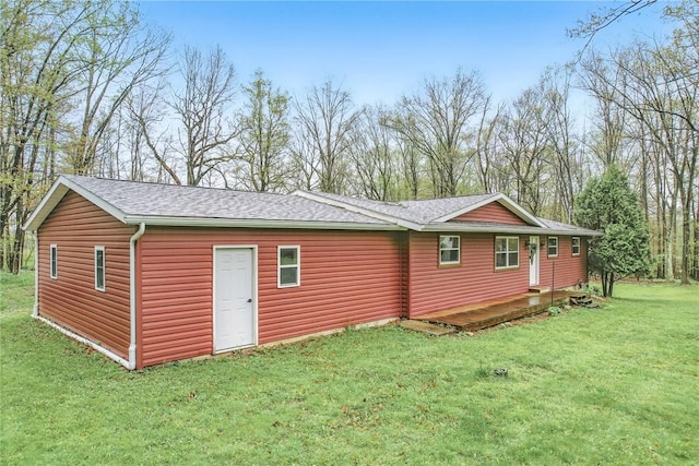 rear view of property with a lawn and a shingled roof