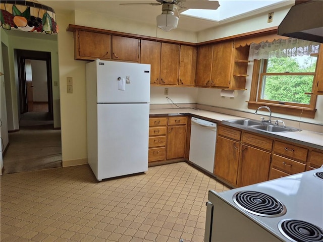 kitchen with white appliances, a sink, brown cabinets, ceiling fan, and a skylight