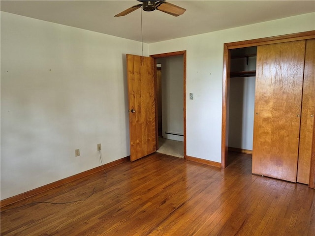 unfurnished bedroom featuring hardwood / wood-style floors, a baseboard heating unit, a closet, baseboards, and ceiling fan