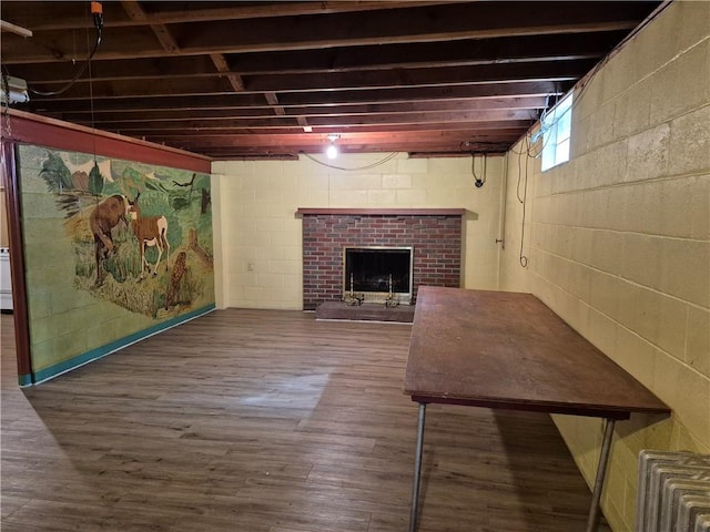 basement featuring a brick fireplace and wood finished floors