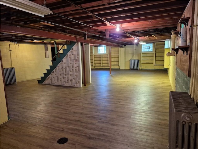 basement with stairway, healthy amount of natural light, and wood finished floors