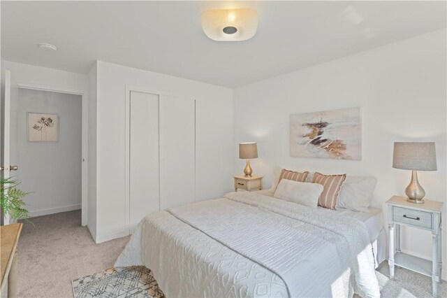 bedroom with light colored carpet, a closet, and baseboards