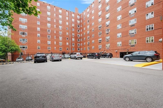 view of apartment building / complex with uncovered parking and fence