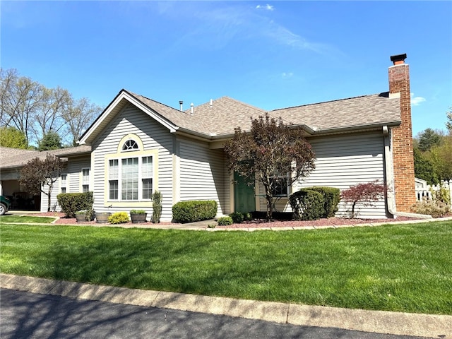 ranch-style house featuring a front yard, a chimney, and roof with shingles