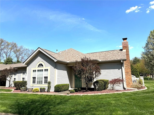 view of front of house featuring a chimney, a front lawn, and a shingled roof
